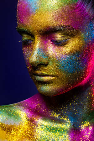 Beautiful girl in colorful bright sequins and colorful lights posing in the Studio . Art design...