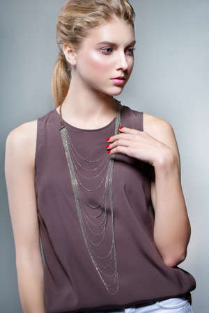 Beauty fashion portrait of a young beautiful girl posing in the Studio. Bright evening makeup, stylish clothes. Hand touches decorationの写真素材