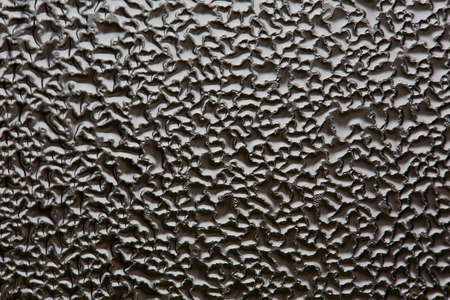 monochrome abstraction blurry drops of water on the glass. dark background for design. macro. beautiful pattern on glassの写真素材