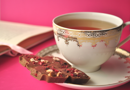 Chocolate tea cup and book on bright pink with copy space
