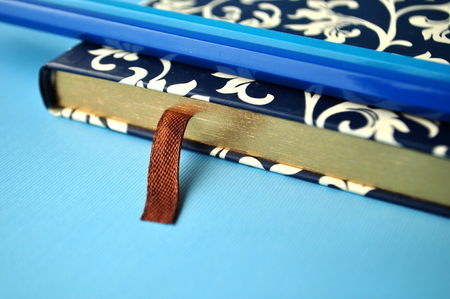 Floral notebook and a blue silver pen on blue flat layの写真素材