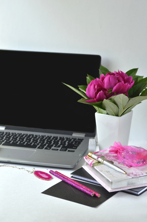 Bold pink peonies on white and black theme creative workspace with stationery closeup. Freelancing and working from home. Feminine creative work desktop.の写真素材