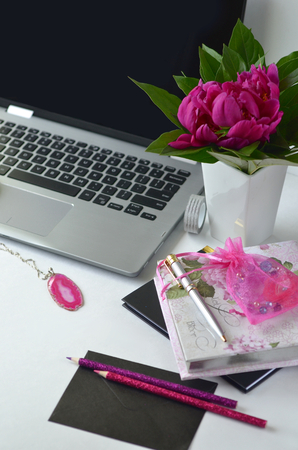 Bold pink peonies on white and black theme creative workspace with stationery closeup. Freelancing and working from home. Feminine creative work desktop.の写真素材