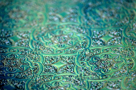 Dark blue green turquoise teal ornamental filigree pattern in gold and silver metallic vivid color with blurred background and selective focus. Copy space.の写真素材