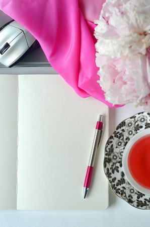 Elegant styled feminine desktop - relaxation, reading, creative writing, learning and journaling concept - with pink peonies, fruit tea and stylish stationeryの写真素材