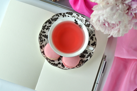 Elegant styled feminine desktop - relaxation, reading, creative writing, learning and journaling concept - with pink peonies, fruit tea and stylish stationeryの写真素材