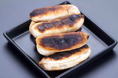 Thai dessert - roasted or grilled banana on black plateの写真素材