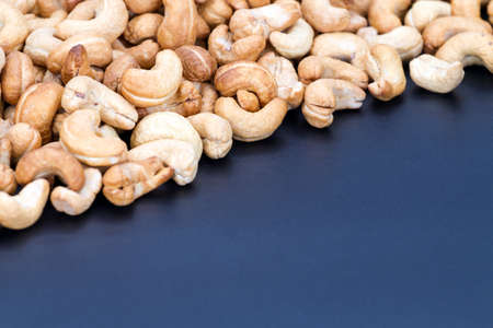 Roasted pile of cashew nuts on black plateの写真素材
