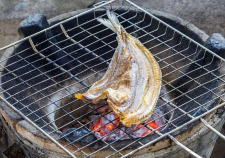 Grilled dried snake-head fish on hot red charcoalの写真素材