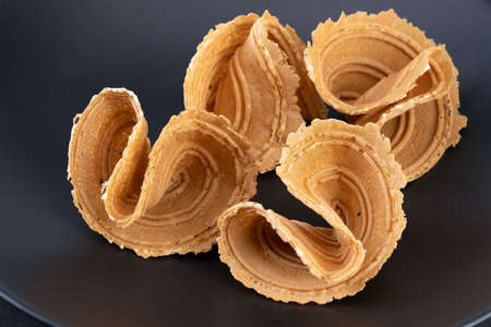 Thai appetizer (Thong pup - golden fold) is sweet and crispy made from flour, coconut milk, sugar, sesame, salt on a black plate.の写真素材