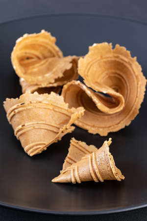 Thai appetizer (Thong pup - golden fold) is sweet and crispy made from flour, coconut milk, sugar, sesame, salt on a black plate.の写真素材