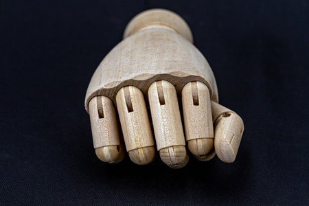 A Wooden puppet hand showing a fist, the idea of making a gesture of power or greeting on a black...