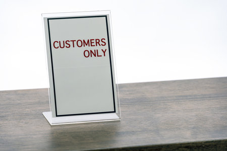 A customers only sign is displayed on wooden table, emphasizing exclusivity and access restriction. sign is simple and clear, set against neutral backgroundの写真素材