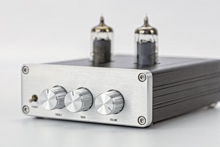 A silver audio amplifier with vacuum tubes metal front panel three control knobs modern design isolated on white background high fidelity retro style clean shiny elegantの写真素材