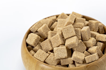 An organic brown sugar cubes in wooden bowl isolated on white background natural sweetener healthy ingredient rustic kitchen close up food concept clean eating minimal styleの写真素材