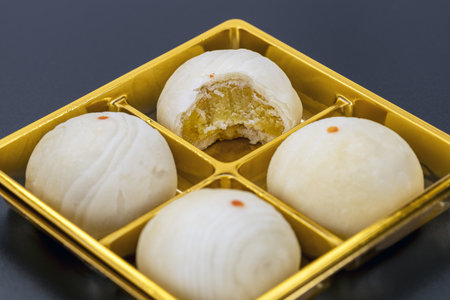 A chinese mooncakes filled with bean paste, one with bite taken, displayed on golden tray, showcasing traditional dessert with soft texture and sweet flavorの写真素材