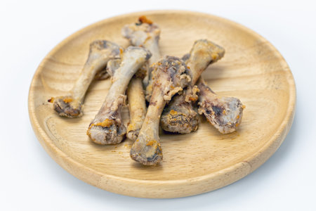 A chicken bone leftover wooden plate white background food waste cooked closeup horizontal unhealthy...
