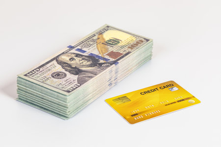 A stack of cash and yellow credit card on white background showing financial concept and confident...
