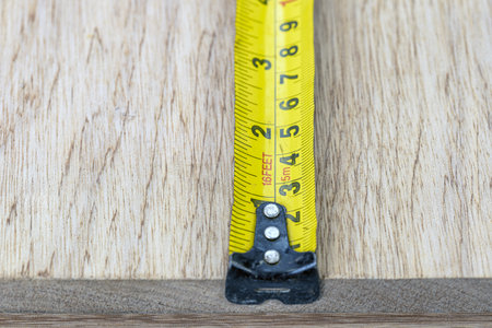 A measuring tape yellow metal wood closeup tool metric imperial inch scale snug focus measuring tape...