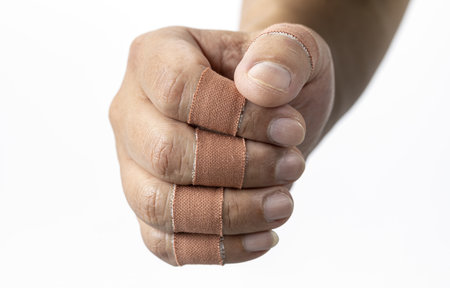 A fist with finger bandages is shown, conveying sense of resilience and healing. bandages are wrapped around fingers, indicating recovery or protectionの写真素材