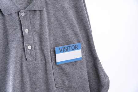 A gray shirt with visitor badge on pocket, featuring blue and white design. shirt is casual polo style, emphasizing professional yet relaxed appearanceの写真素材