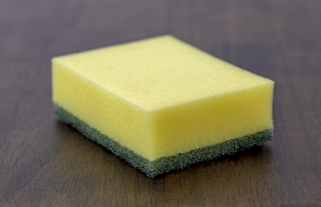 A yellow sponge green scrubber cleaning sponge kitchen sponge dish sponge household cleaning porous texture rectangular shape hygiene tool wood table surfaceの写真素材