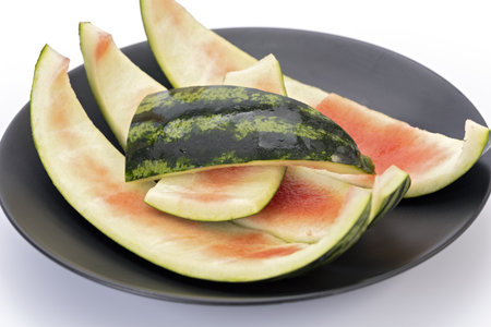 Watermelon rind, which is leftover on a black plate with a white background, is an ingredient in...
