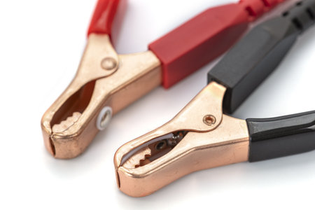 A close up of two alligator clips with red and black handles on white background, used for electrical connections. metal clamps are open, showing their teethの写真素材