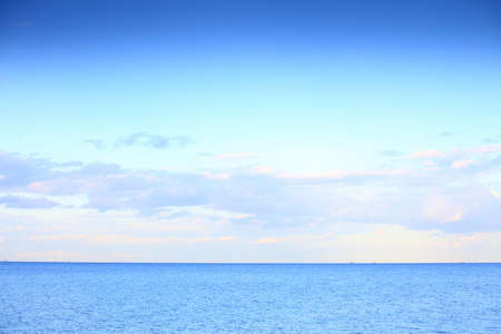 cloudy blue sky leaving for horizon above a blue surface of the seaの写真素材