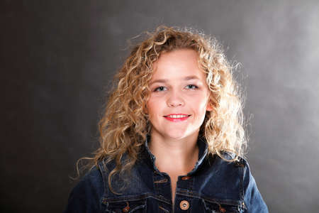 Young beautiful woman with long curly blond hair on grey backgroundの写真素材