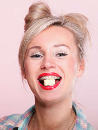 Cheerful pin up girl retro style portrait pinup Woman eating chocolate pink background