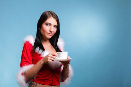 cheerful santa claus woman Girl blowing on hot drink  blue backgroundの写真素材