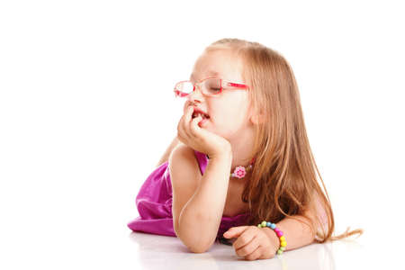 cheerful little girl glasses funny is lying isolated on the white backgroundの写真素材