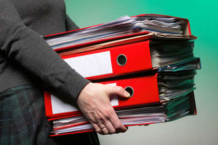 woman in grey holding stack of folders. Pile with old documents and bills on green background