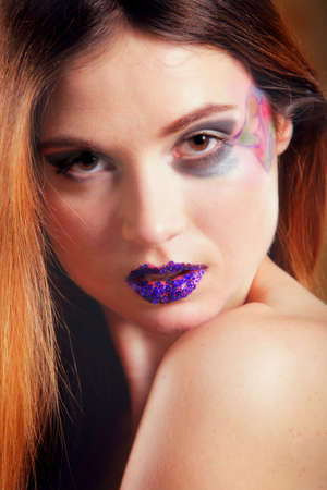 portrait of young beautiful woman long hair colorful make up brown backgroundの写真素材