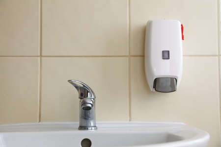 White sink tap and liquid soap in the bathroomの写真素材