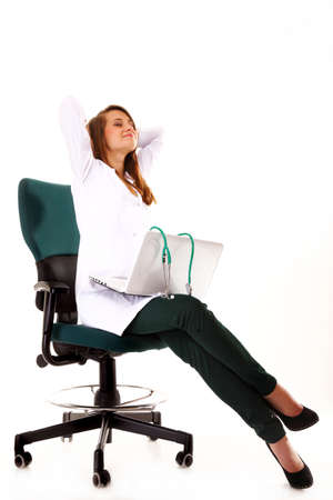 Female doctor working on her laptop stretching at her workplace against a white backgroundの写真素材