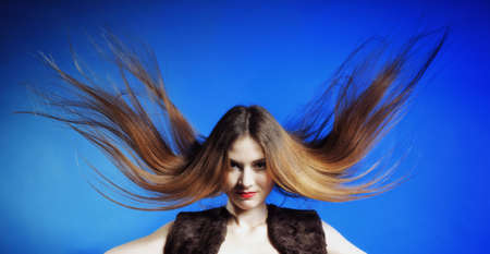 Fashion model with hair blowing in the wind blue backgroundの写真素材