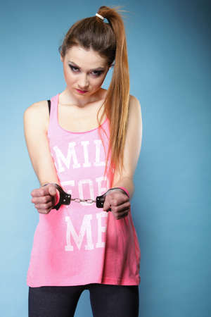 teen crime - teenager girl in handcuffs studio shot blue backgroundの写真素材