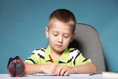little boy drawing with color pencils on blue background