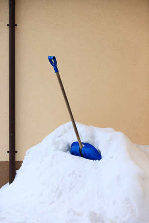 blue snow shovel standing up in deep snow, winter sceneryの写真素材