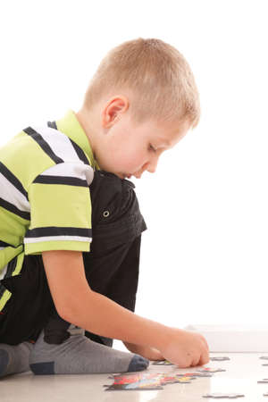 Child boy playing puzzle on floor isolated on white backgroundの写真素材