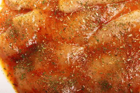 Closeup raw marinated chicken breasts with spices and herbs as backgroundの写真素材