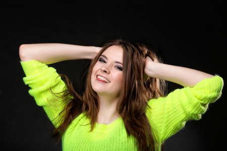 Grimacing young happy woman making silly face sticking out her tongue on black backgroundの写真素材