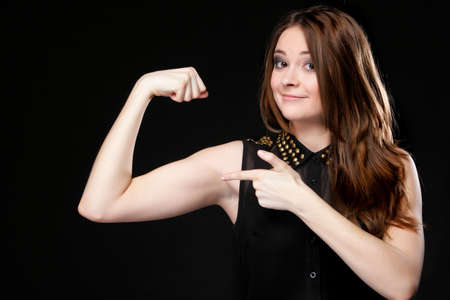 woman long hair shows her muscles black background strength and power conceptの写真素材