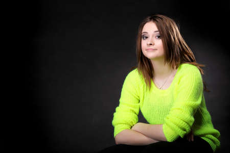 Portrait young woman wearing bright vivid colour sweater on black backgroundの写真素材
