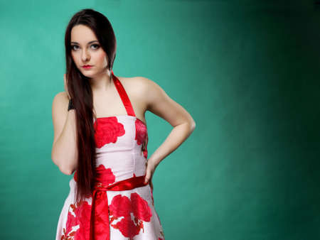 young woman in summer flowery dress on green background fashion photoの写真素材