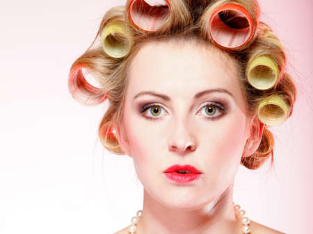 Sexy woman preparing to party, girl with curlers in hair and beads pink backgroundの写真素材