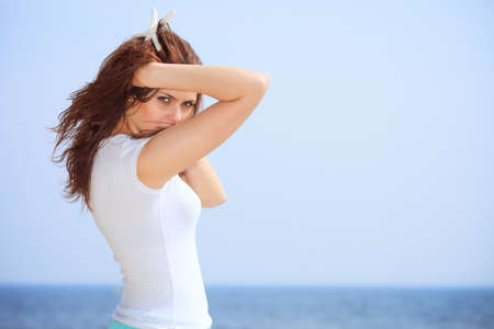Young woman on seacoast with starfish in hand- -summer vacationの写真素材