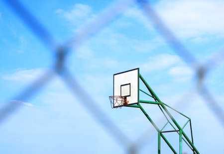 basketball basket on cloudy blue sky background and blur metal mesh, wire fenceの写真素材